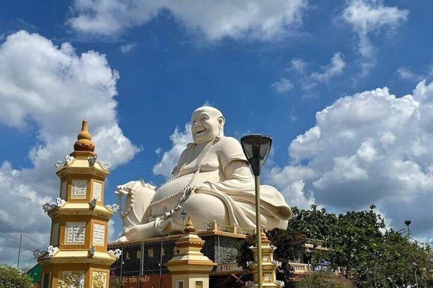 A large white statue of a seated figure, a pagoda, and a street lamp. 4