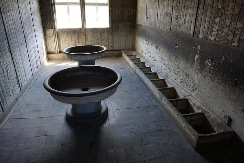 A dilapidated room with two large, empty basins and a set of stairs leading to a window. 4