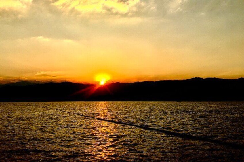 A sunset over a body of water with a silhouette of hills in the background. 5