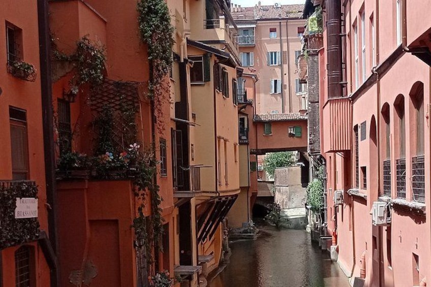 Eine schmale Straße mit Gebäuden an beiden Seiten, ein Kanal in der Mitte und eine Brücke in der Ferne. 3