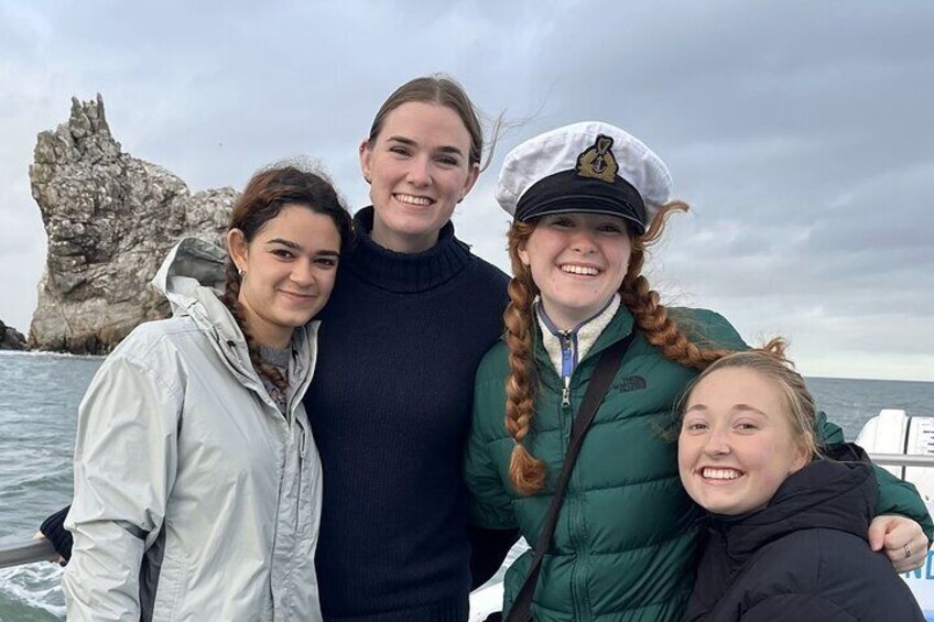 Four people on a boat with a rocky coastline in the background. 3