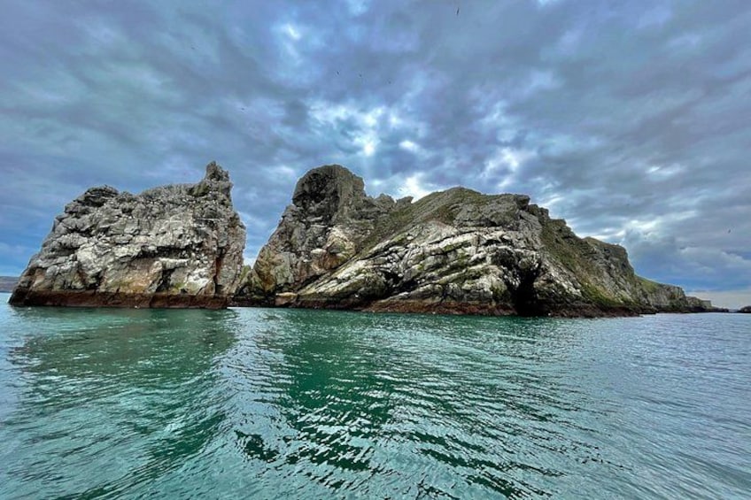 Eine felsige Insel mit einer Höhle, umgeben von türkisblauem Wasser. 2