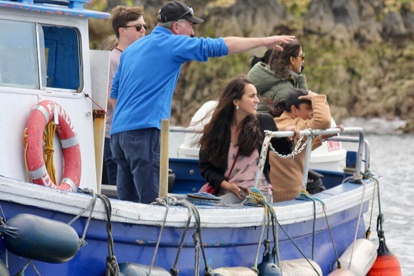 Un bote con gente a bordo, un flotador salvavidas y una costa rocosa al fondo. 2