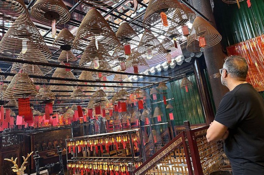 Un interior tradicional con estructuras cónicas colgantes, adornos rojos suspendidos y una persona observando. 2