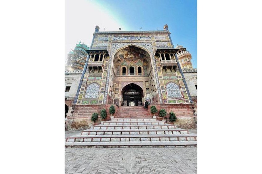 A grand entrance with intricate tile work, a large archway, and a staircase leading up to it. 4