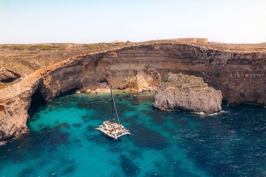 A boat anchored in a natural harbor surrounded by cliffs. 2