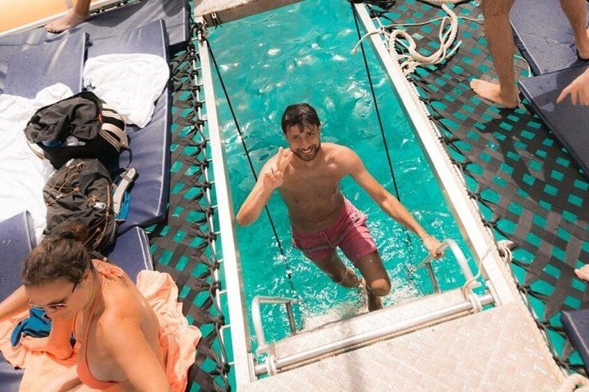 En mand i badeshorts træder ud af en pool og op på et dæk. 1