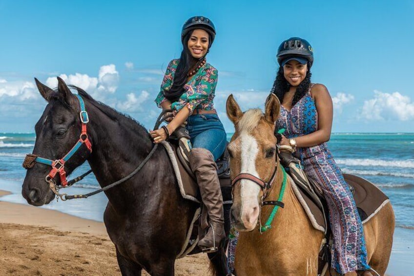 Dos personas montando a caballo en una playa, con el océano al fondo. 3