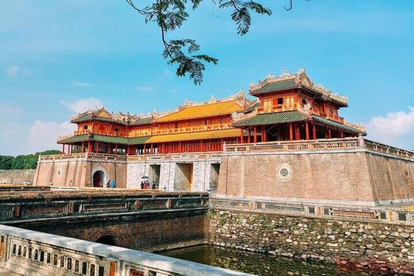 A traditional Chinese building with a yellow roof and red walls, surrounded by a stone wall and a waterway. 1