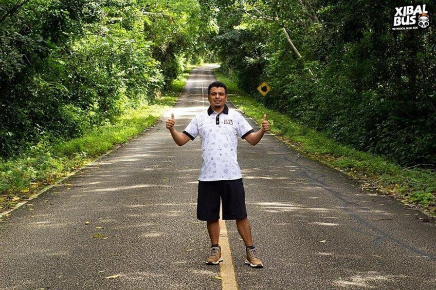 A person standing on a road with greenery on both sides. 3
