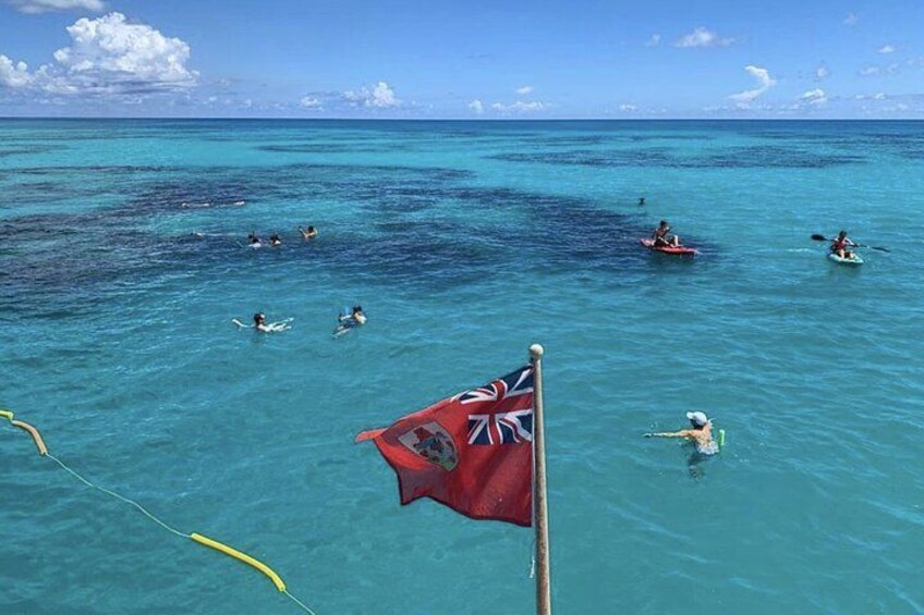 A flag, people kayaking, and a clear blue sea. 2