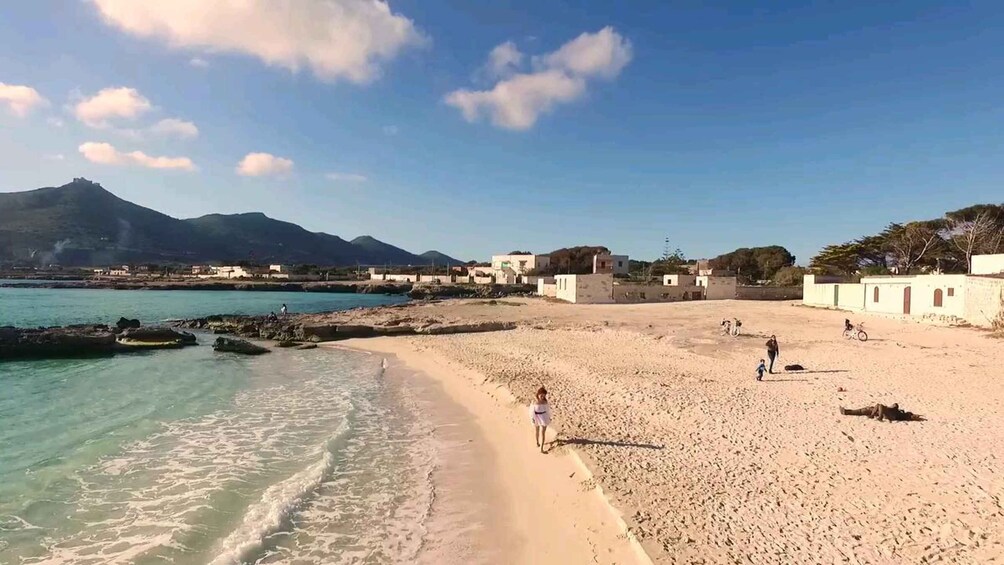 A coastal beach with clear waters, a sandy shore, and a mountain in the background. 5