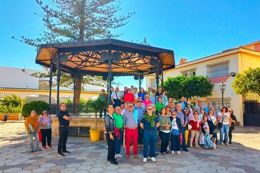 A group of people gathered around a gazebo in an outdoor setting with a clear sky. 1