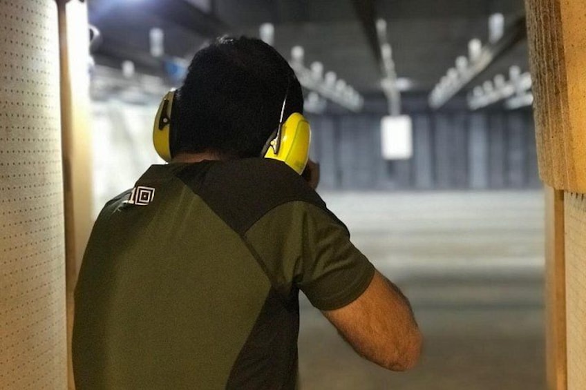A person wearing a green shirt and yellow headphones, standing in a dimly lit indoor space with a concrete floor and metal beams. 4