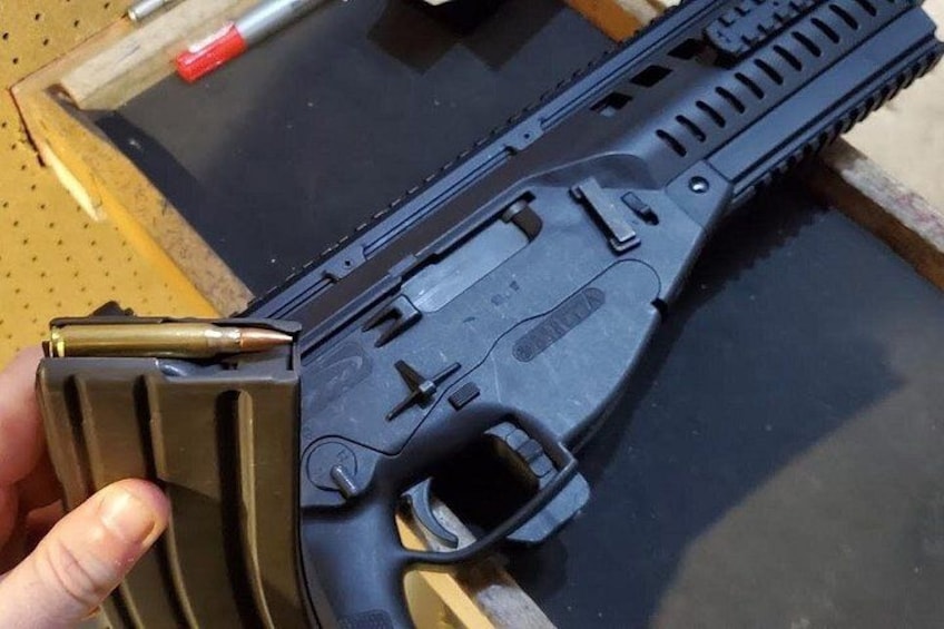 A firearm with a magazine loaded with bullets, a trigger, and a grip. 5