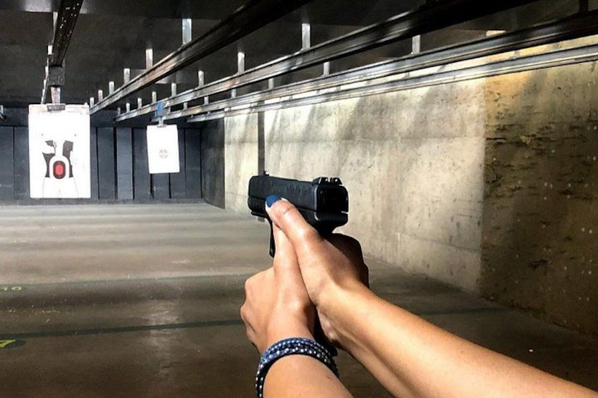A person holding a handgun at a shooting range with targets in the background. 1