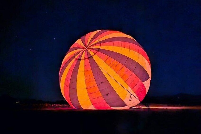 A hot air balloon with a red and orange striped pattern, tethered to the ground. 4