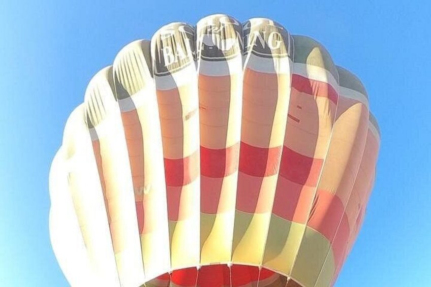 A hot air balloon with a striped pattern against a clear sky. 5