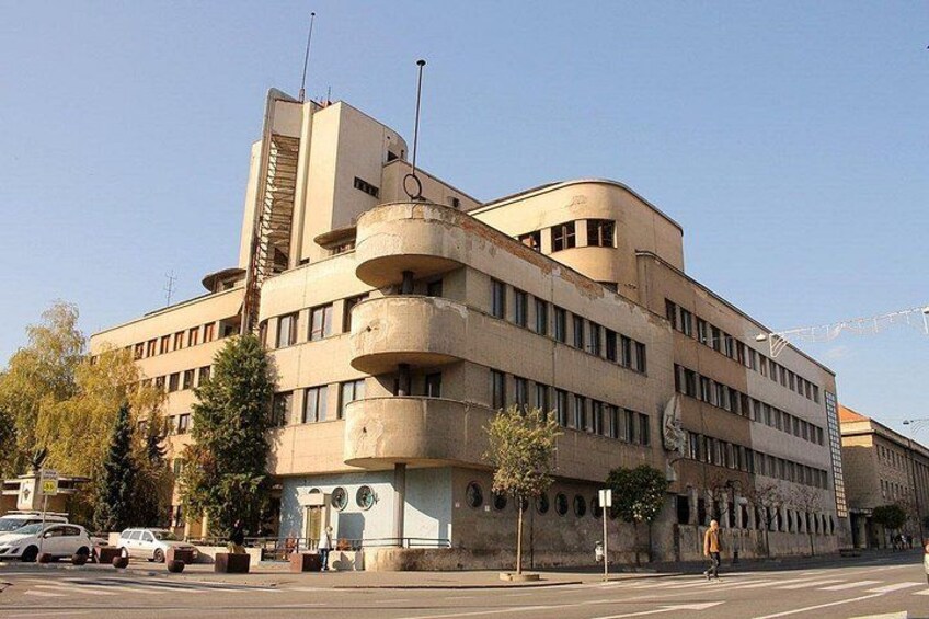 Un edificio de varios pisos con fachada curva, amplios ventanales y una antena destacada. 2