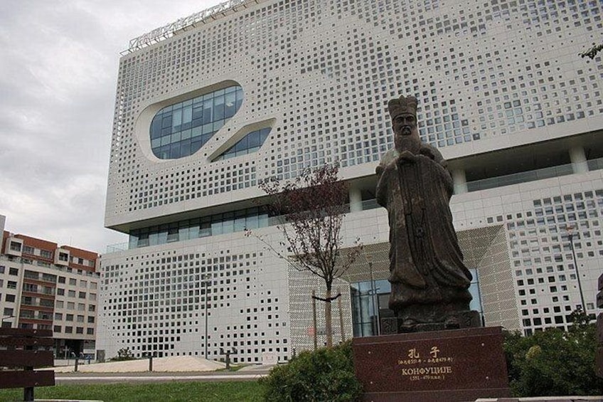 Un edificio moderno con una fachada perforada distintiva y una estatua en su parte frontal. 4