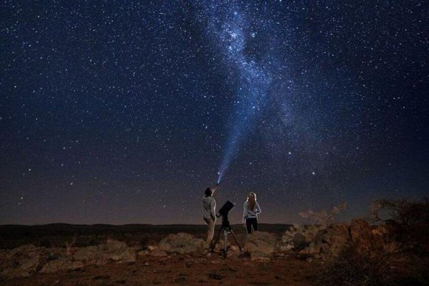 Two people under a starry night sky with a telescope. 1