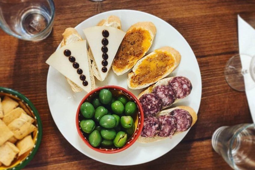 A plate with slices of bread, a bowl of olives, and a bowl of green olives. 1
