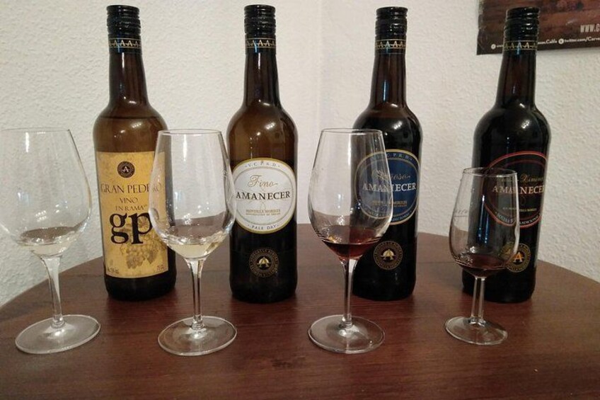 Four wine bottles and three wine glasses on a wooden table. 2