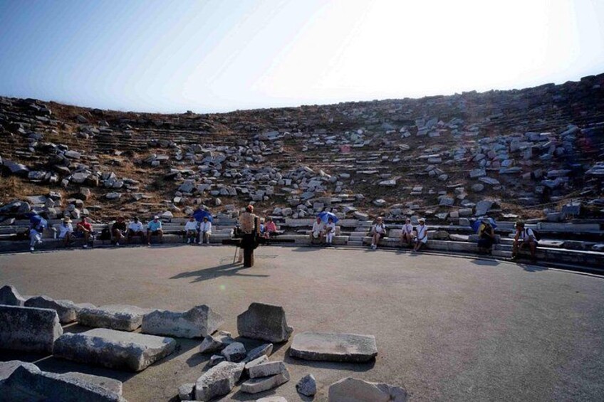 A rocky amphitheater with people sitting and standing. 3