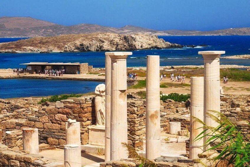 Ancient ruins with columns, a stone wall, and a coastal landscape with a clear sky. 4