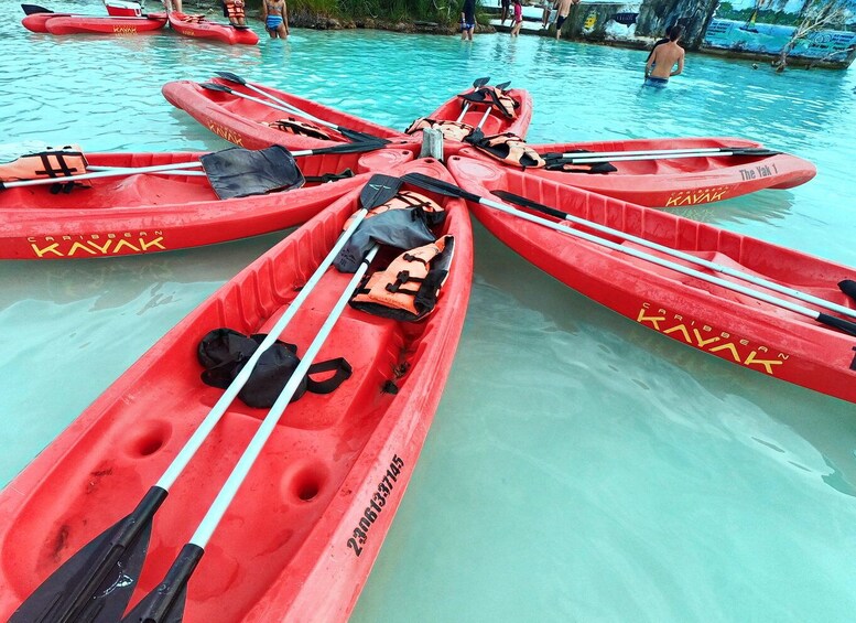 Kayaks rojos con remos y chalecos salvavidas alineados en una piscina. 1