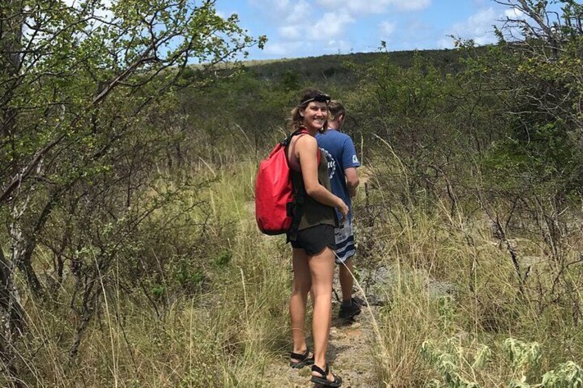 Two people hiking on a trail surrounded by dry grass and shrubs. 5