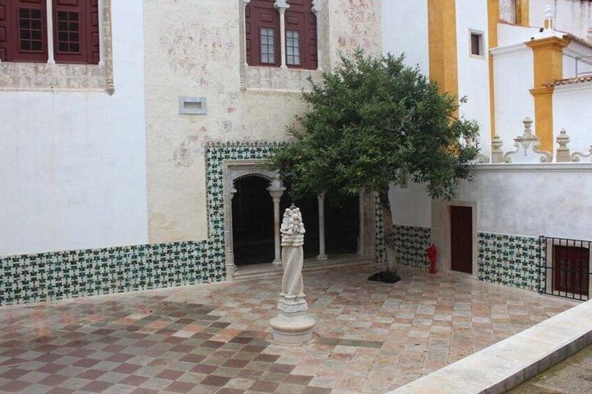 Ein Innenhof mit Fliesenboden, einer Statue und einem Baum. 3