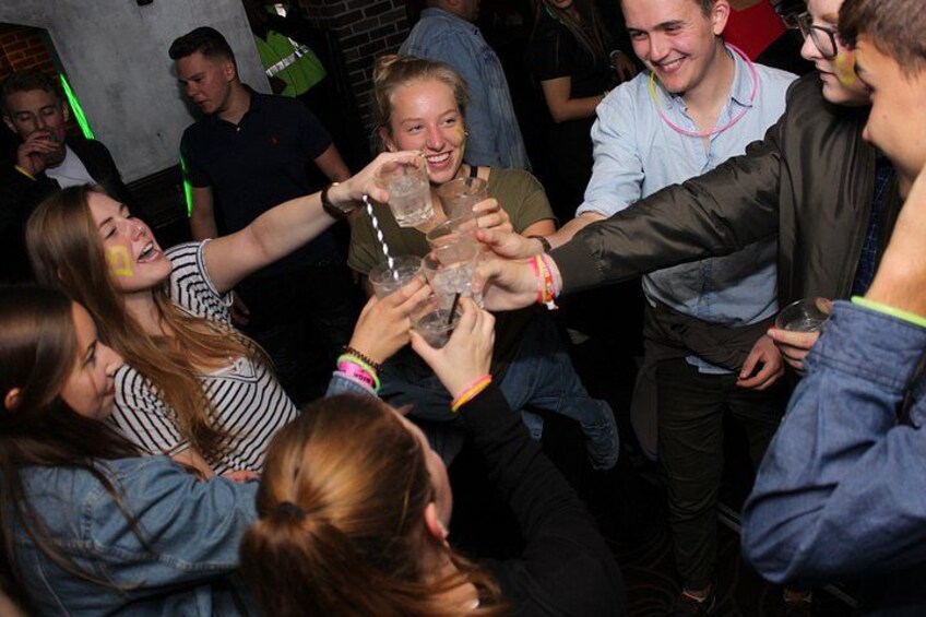 A group of people toasting with drinks in a social setting. 2