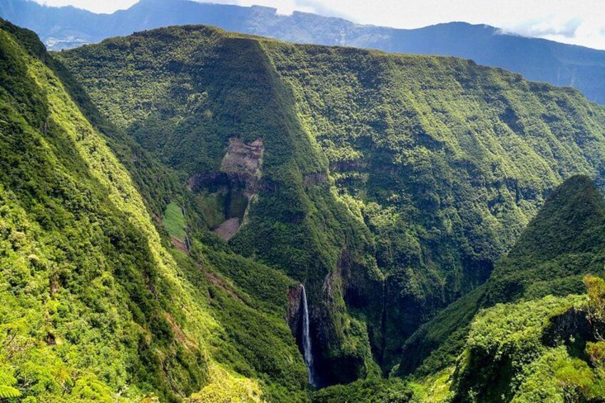 Een weelderig groene vallei met steile heuvels en een waterval. 1