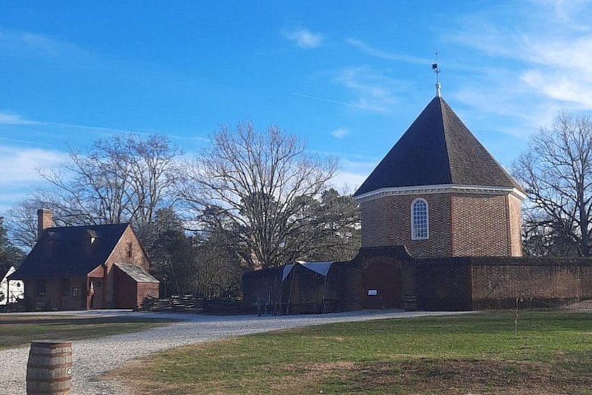 A brick church with a conical roof, a gravel path, and a grassy area. 2