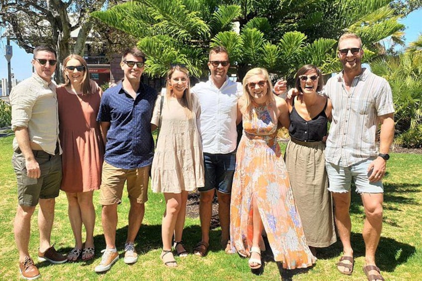 A group of people standing outdoors on grass with trees and a building in the background. 5