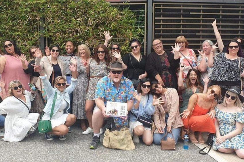 A group of people posing for a photo in an outdoor setting with a building and foliage in the background. 3