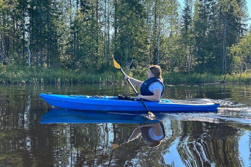 Una persona haciendo kayak en un río tranquilo rodeado de un bosque denso. 4