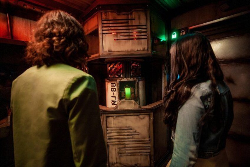 Dos personas de pie frente a un jukebox con una luz verde. 2