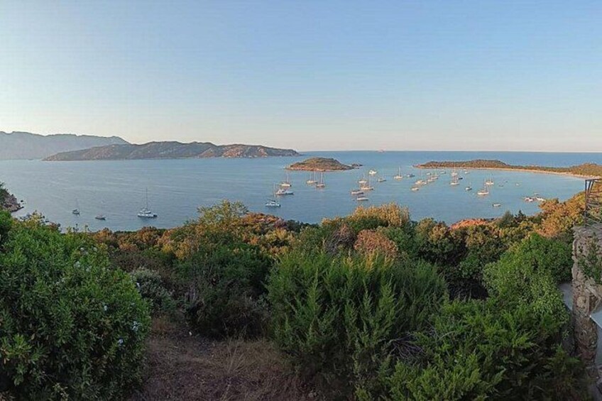 A coastal landscape with boats, greenery, and hills. 2