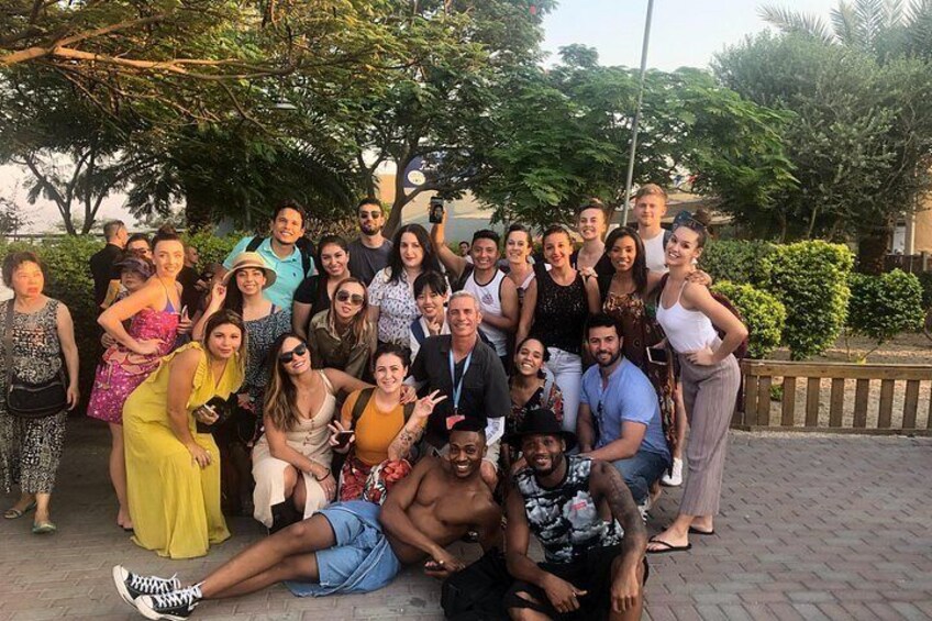 A group of people posing for a photo in an outdoor setting with trees and a paved walkway. 4