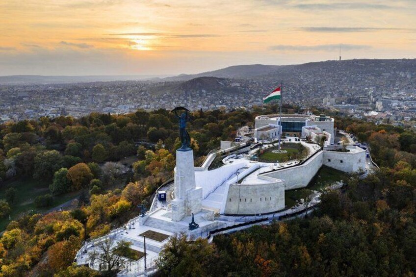 A large white building with a statue in front, surrounded by trees and a flag. 5