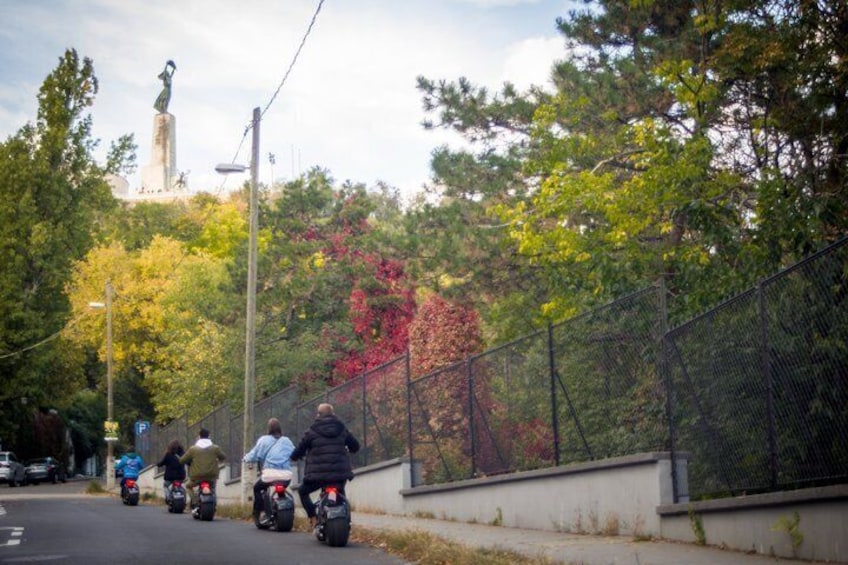 A group of motorcyclists on a road with a statue in the background. 4
