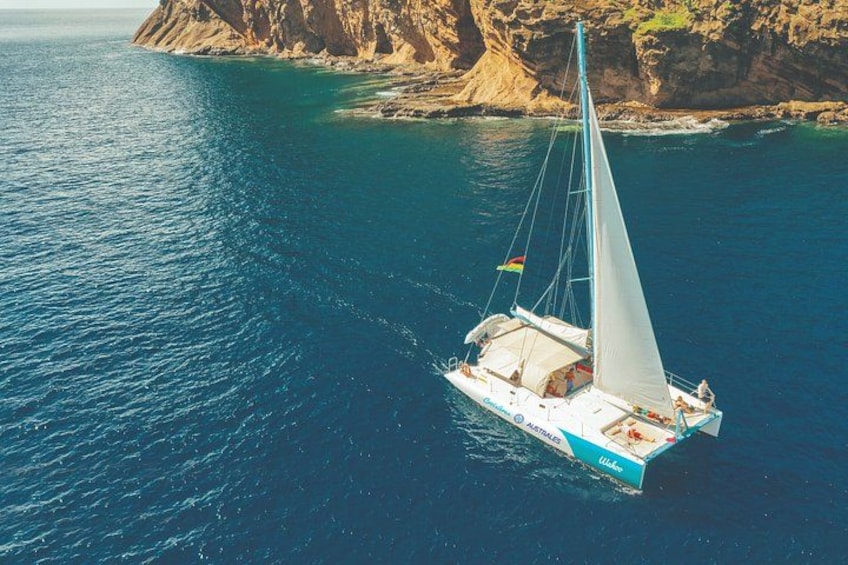 Un velero en un mar tranquilo con un litoral rocoso al fondo. 5