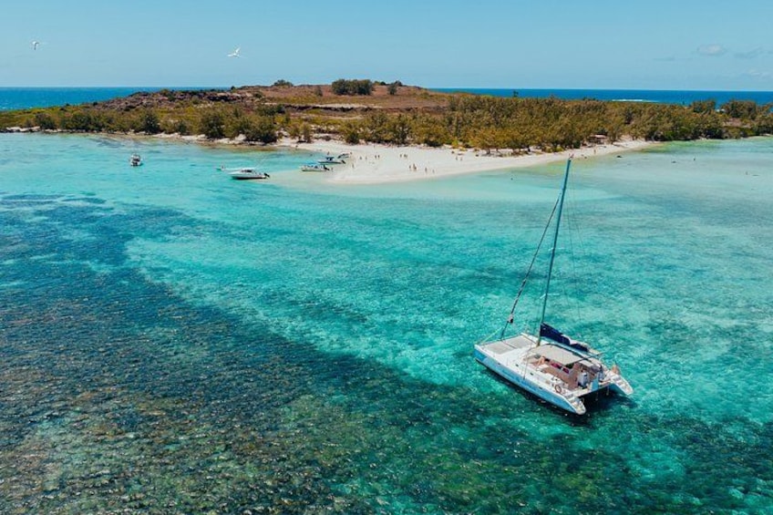 Un mar turquesa transparente con un velero anclado cerca de una playa de arena. 4
