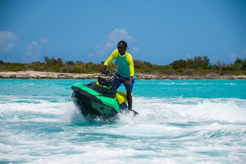 A person riding a green and black jet ski on turquoise water. 4