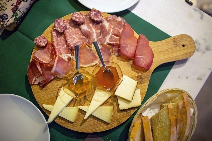 Una tabla de embutidos con diferentes carnes, queso y miel. 3
