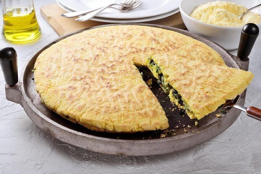 Una quiche en una sartén de hierro fundido con una porción retirada, mostrando un relleno verde. 2
