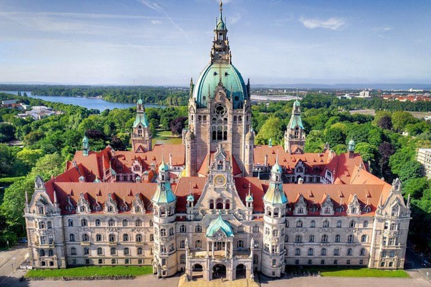 Un edificio storico con una grande cupola e numerose guglie, circondato da una vegetazione rigogliosa e un lago sullo sfondo. 5