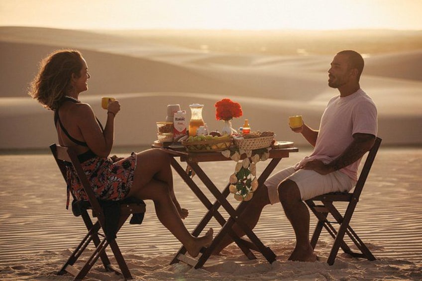 Two people sitting at a table with a meal in a desert setting. 5